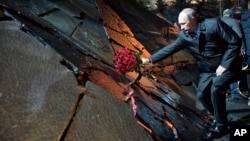Russian President Vladimir Putin, lays a bunch of flowers as he he attends a ceremony unveiling the country's first national memorial to victims of Soviet-era political repressions called "The Wall of Grief" in Moscow, Russia, Oct. 30, 2017. 