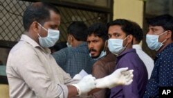 People in the southern Indian state of stand outside a hospital wearing masks to protect themselves against the Nipah virus, May 21, 2018.