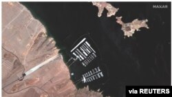 A combination of two images show aerial views of the Hemenway Harbor boat launch area on Lake Mead and Hoover Dam on the Colorado River on May 18, 2020 (top) and on July 27, 2021 (bottom).