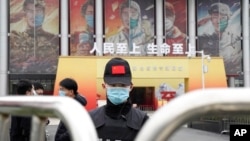 A security officer wearing a mask and a cap with the Chinese national flag guards the entrance after a World Health Organization team's arrival at an exhibition on the fight against the coronavirus, in Wuhan, China, Jan. 30, 2021. 