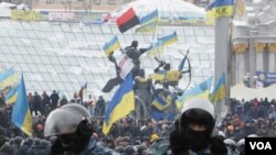 Pengunjuk rasa integrasi pro-Uni Eropa berdiri di belakang barisan polisi anti huru hara di Lapangan Kemerdekaan di Kiev, Ukraina (11/12).