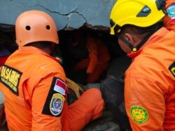 Members of a search-and-rescue agency team dig through rubble after an earthquake, in Mamuju, West Sulawesi Province, Indonesia, Jan. 15, 2021. (Basarnas Sulbar/via Reuters)