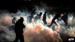 FILE - Palestinian protesters run from tear gas fired by Israeli forces amid clashes during a demonstration along the border with Israel east of Bureij in the central Gaza Strip, Dec. 6, 2019. 
