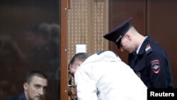Defendant Pavel Ustinov, accused of using violence against an officer of Russia's National Guard during an unauthorized rally to demand free elections, listens to a lawyer during a court hearing in Moscow, Sept. 16, 2019.