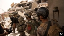 FILE - Iraqi special focus advance to their next position in the Islah al-Zarai area in Mosul, Iraq, May 11, 2017. 