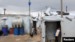 FILE - A Syrian refugee boy stands in front of a tent at an informal tented settlement in the Bekaa valley, Lebanon, March 12, 2021. 