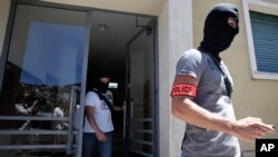 Des policiers français en cagoule emportent des documents lors d’une perquisition au domicile de Mohamed Lahouaiej Bouhlel, l’auteur présumé de l’attaque de Nice, dans sud de la France, 16 juillet 2016. (AP Photo / Luca Bruno)