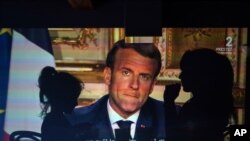 A family watches French President Emmanuel Macron's televised speech, Monday April 13, 2020, in Lyon, central France.