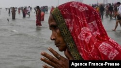 A Hindu pilgrim in India prays as she takes a holy dip at the confluence of Ganges and the Bay of Bengal during the Gangasagar Mela on the occasion of Makar Sankranti, Jan. 14, 2022. 