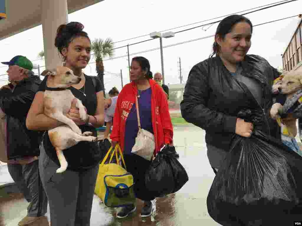 Rescued from flooding, people with their pets prepare to board a school bus bound for the M.O. Campbell Educational Center in north Houston, Texas, Aug. 27, 2017. The multipurpose facility is serving as a Red Cross shelter. (C. Mendoza/VOA)
