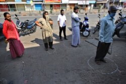 Indians stand in marked positions to maintain physical distance outside a grocery store during lockdown in Bangalore, India, March 26, 2020.