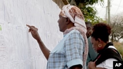 Kenyans check names on the electoral lists at a polling station in the Nairobi South C, in Nairobi, Kenya, Aug. 7, 2017.