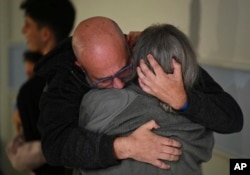 FILE - Sharon Hertzman, right, hugs her husband, Hen Avigdori, as they reunite in Ramat Gan, Israel, on Nov. 25, 2023. Sharon Hertzman and her 12-year-old daughter, Noam, not pictured, were released by Hamas after being held as hostages in Gaza for 50 days. (Haim Zach/GPO via AP)