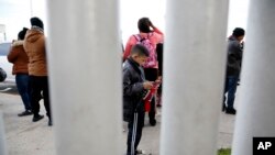 FILE - A migrant family waits with others before being transported by Mexican authorities to the San Ysidro port of entry to begin the process of applying for asylum in the United States, in Tijuana, Mexico, Jan. 29, 2019.