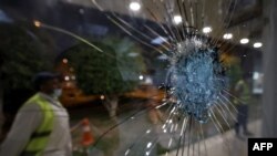 Saudi airport personnel are pictured behind shrapnel-riddled glass at Abha airport in the popular mountain resort of Abha in the southwest of Saudi Arabia on August 31, 2021.