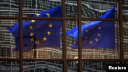 FILE - A European flag reflects in a building of the EU headquarters in Brussels.