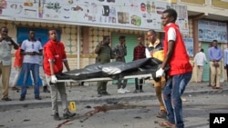 Medical workers remove the body of a civilian who was killed in a car bomb explosion near the parliament building in the capital Mogadishu, Somalia, March 25, 2018. 