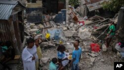 Satu keluarga makan pagi bersama di antara puing-puing rumah mereka pasca gempa di Les Cayes, Haiti, Minggu (15/8). 