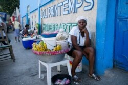 Food vendor Marie Bernard Noel sits outside the closed Center Classique Don Bosco school, in hopes it might reopen, in Petion-Ville, Haiti, Dec. 2, 2019.