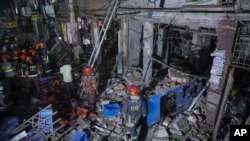 Rescuers stand amid the debris after a blast at a market in Dhaka, Bangladesh, June 27, 2021. 
