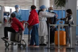 Health workers screen people entering the Capital International Airport terminal 3 in Beijing, March 12, 2020.