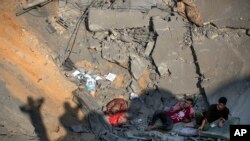 Palestinians sit amid the rubble of their destroyed house following overnight Israeli missile strikes, in the town of Khan Younis, southern Gaza Strip, Nov. 14, 2019. 