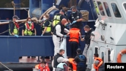 FILE - Migrants disembark after arriving at Dover harbor, in Dover, Britain, Aug. 12, 2020.