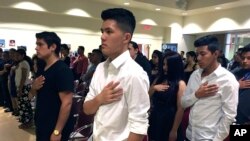 FILE - Long Chi Vong, 16 (C), from Albuquerque, and other immigrants stand for the U.S. Pledge of Allegiance before taking the Oath of Citizenship at a ceremony in Rio Rancho, N.M., Aug. 19, 2016