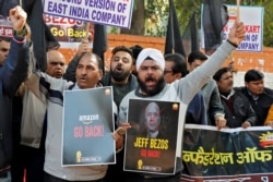 Members of the Confederation of All India Traders (CAIT) hold placards and shout slogans during a protest against the visit of Jeff Bezos, founder of Amazon, to India, in New Delhi, Jan. 15, 2020.