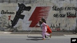 Bocah-bocah di jalanan Manama berlari membawa bendera Bahrain, Sabtu. Di belakang mereka, terlihat slogan-slogan anti-F1.