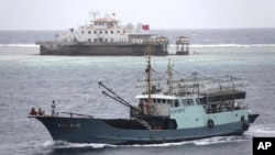 In this photo taken on July 20, 2012, a fishing boat sails past the Meiji reef off the island province of Hainan in the South China Sea. China's newest city, on a small, remote island in the South China Sea, is also claimed by Vietnam.