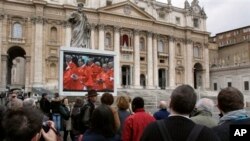 Para pengunjung menyaksikan penayangan misa di Gereja Basilica Santo Peter melalui layar monitor di Lapangan Vatikan. Misa ini diadakan sebelum para kardinal mengasingkan diri di dalam lapel Sistine dalam konklaf untuk memilih Paus baru, 12 Maret 2013. (AP Photo/Michael Sohn)