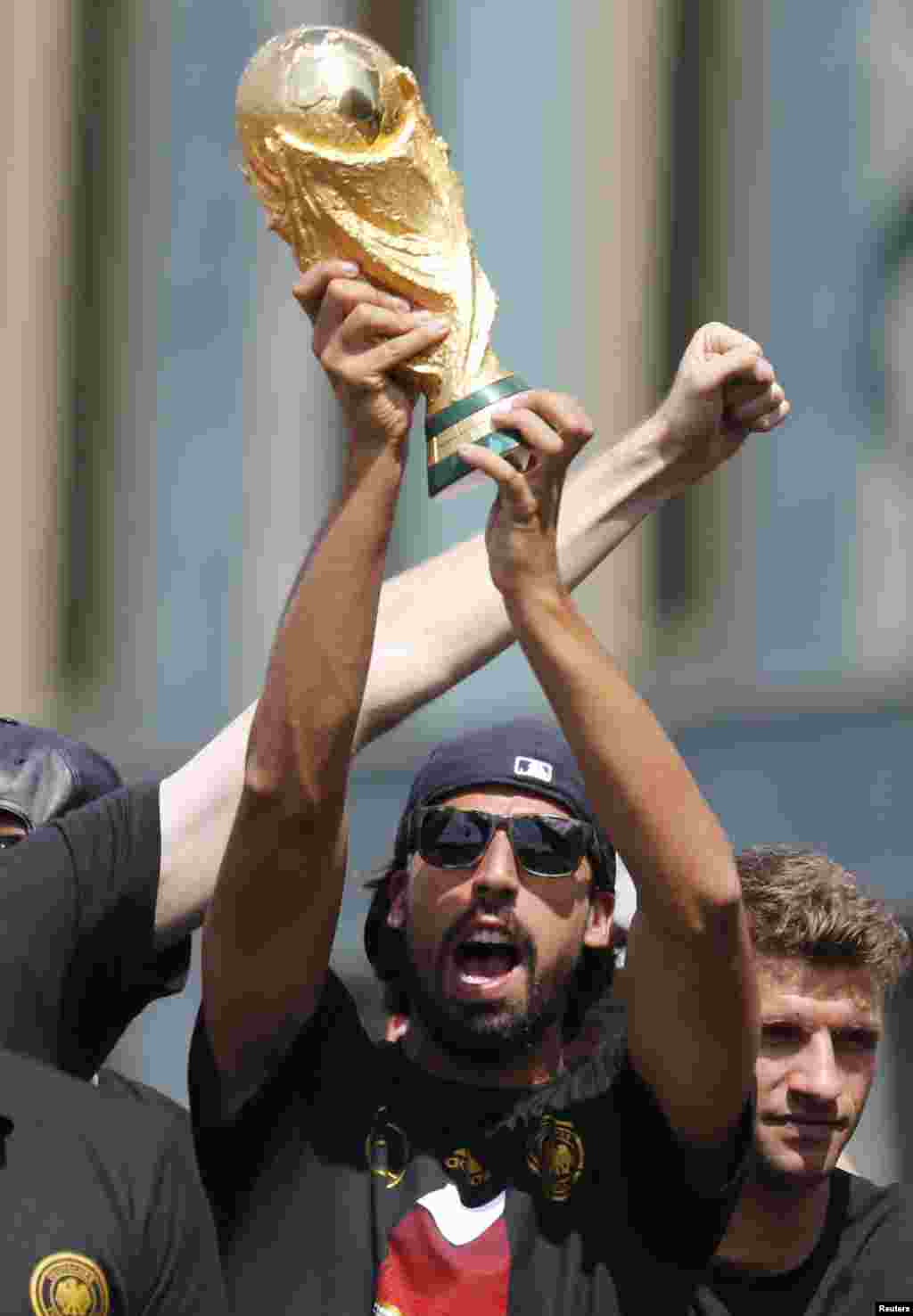 Germany&#39;s national soccer team player Sami Khedira lifts up the World Cup trophy on stage during celebrations to mark the team&#39;s 2014 Brazil World Cup victory, at the Fan Mile public viewing zone in Berlin, July 15, 2014.