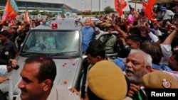 Narendra Modi, kandidat Perdana Menteri India dari partai Bharatiya Janata (BJP), memberikan 'salam damai' kepada para pendukungnya dari dalam mobil yang membawanya dari bandara New Delhi menyusuri pusat kota (17/5).