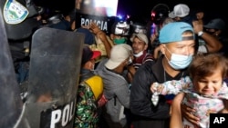 Pasukan keamanan Guatemala (kiri) memblokir perbatasan untuk menghalangi rombongan migran Honduras memasuki negara itu, Minggu (17/1). 