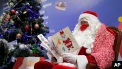 A postal worker dressed as Santa, reads letters to addressed to "Pere Noel" - Father Christmas in French - decorated with love hearts, stickers and glitter, in Libourne, southwest France, Monday, Nov. 23, 2020. (AP Photo/Francois Mori)