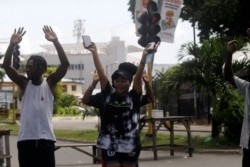 FILE - People raise their hands as they approach a police checkpoint in Lagos, Nigeria, Oct. 22, 2020.