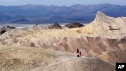 In this April 11, 2010 file photo, tourists walk along a ridge at Death Valley National Park, Calif. Preliminary data show that Death Valley set the world record for hottest month in July 2018.
