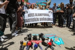 FILE - Reporting equipment lies on the ground outside the offices of Ankara’s government, and protesters hold a banner that reads "We can’t breathe. Journalism cannot be drowned” during a rally calling for journalists to be protected from police, June 29, 2021.