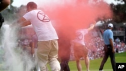 Protesters run onto the course as Scottie Scheffler, right, walks away on the 18th hole during the final round of the Travelers Championship golf tournament at TPC River Highlands, June 23, 2024, in Cromwell, Conn.