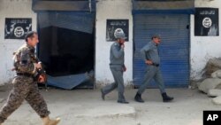 FILE - Afghan police walk past Islamic State militant flags on a wall, after an operation in the Kot district of Jalalabad province east of Kabul, Aug. 1, 2016. China, Pakistan and Russia will meet in Moscow, Dec. 27. 2016, to review "gradual growing" threat of Islamic State from spreading beyond Afghanistan.