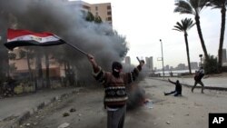 A protester part of the Black Bloc, holds the Egyptian national flag during clashes with riot police near Tahrir Square, Cairo, Egypt, Jan. 28, 2013.