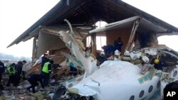 In this handout photo provided by the Emergency Situations Ministry of the Republic of Kazakhstan, police and rescuers work on the side of a plane crash near Almaty International Airport, outside Almaty, Kazakhstan, Dec. 27, 2019.