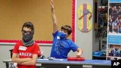 Amid concerns of the spread of COVID-19, Aiden Trabucco, right, wears a mask as he raises his hand to answer a question behind Anthony Gonzales during a summer STEM camp at Wylie High School Tuesday, July 14, 2020, in Wylie, Texas. (AP Photo/LM Otero)