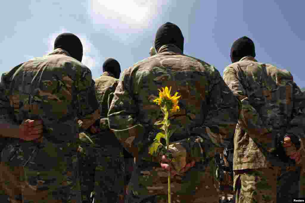 A new volunteer of the Ukrainian self-defense battalion &quot;Azov&quot; holds a sunflower during a ceremony. He will take an oath of allegiance to his country during the ceremony, in Kyiv, July 16, 2014.