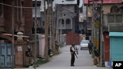 Tentara paramiliter India berlindung saat melakukan pencarian di sebuah perumahan penduduk saat terjadinya bentrokan di Srinagar, Srinagar, Indian Kashmir (13/3). 