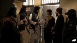 تفنگداران طالبان در حال صحبت با یک زندانی پیش از انتقال وی به سمت محکمه، ۱۹ سپتمبر ۲۰۲۱