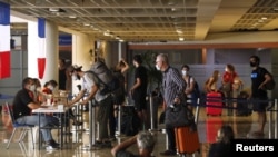 Visitors queue to register their documents with a French Embassy officer before their chartered flight back to their country, amid the spread of COVID-19, at Ngurah Rai International Airport in Bali, Indonesia, March 28, 2020.
