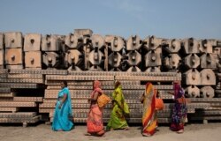 Devotees walk past the pillars that Hindu nationalist group Vishva Hindu Parishad (VHP) say will be used to build a Ram temple at the disputed religious site in Ayodhya, India, Oct. 22, 2019.