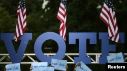 Para pendukung mengangkat simbol kampanye sambil menunggu kedatangan calon presiden dari Partai Demokrat, Hillary Clinton (5/11). Pembroke Pines, Florida. (foto: REUTERS/Carlos Barria)